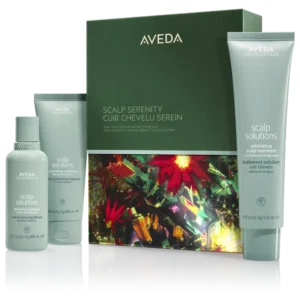 Three Aveda Scalp Solutions haircare products and a matching decorative box are displayed side by side, complemented by an Aveda pink ribbon hand cream against a white background.