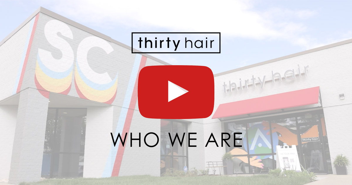 A salon building with "thirty hair" signage, a red awning, and a large play button overlaid with the text "WHO WE ARE.
